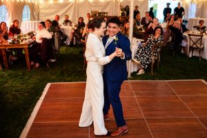 Bride and groom share their first dance on a wooden dance floor at wedding reception.