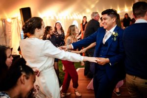 Bride and groom joyfully dance together surrounded by guests at wedding reception.