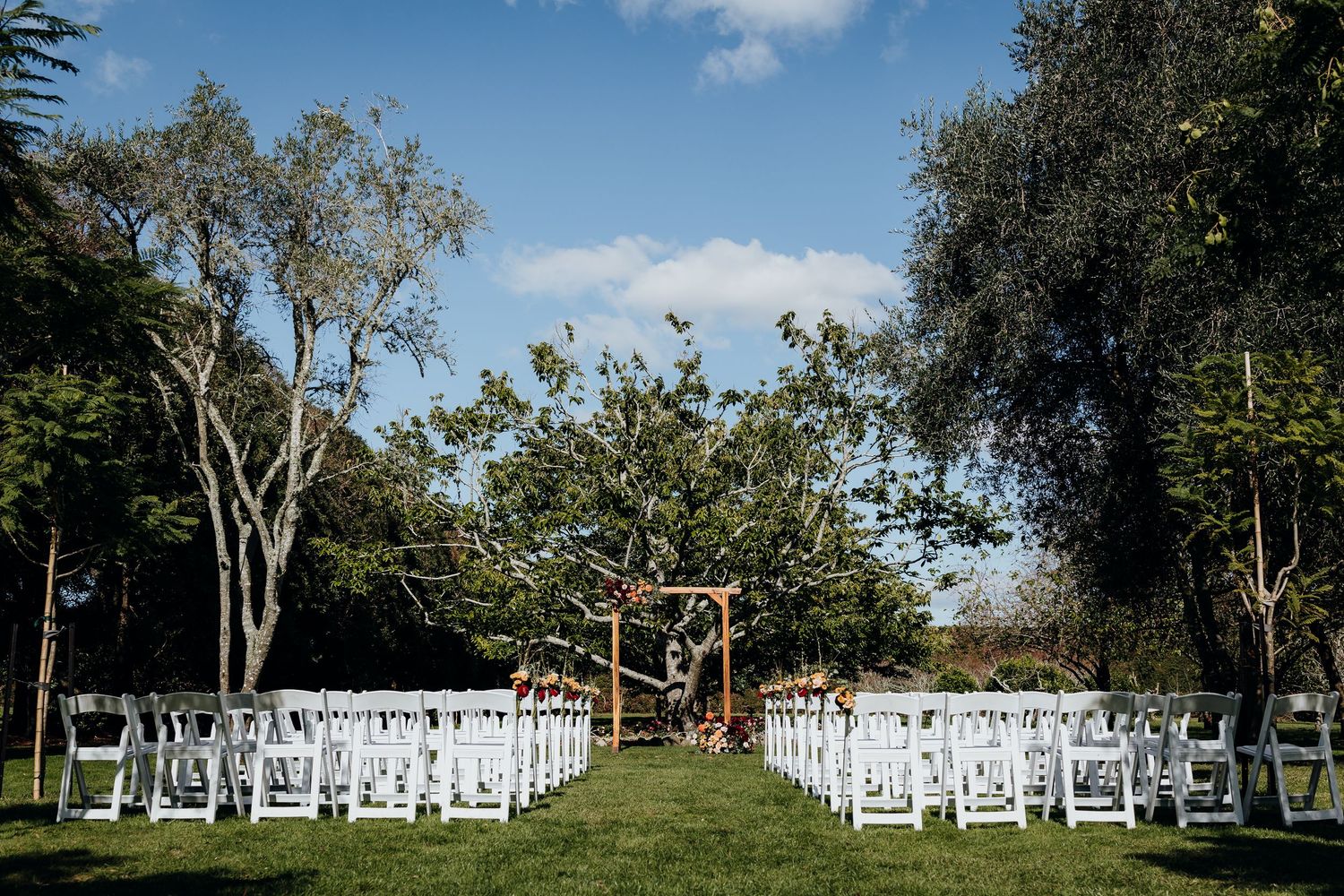 Wedding guests toss colorful confetti in celebration during an outdoor ceremony.