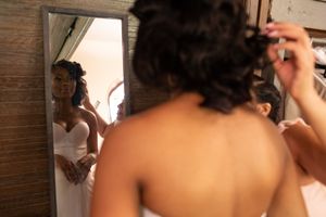 Getting ready scene showing final wedding dress preparations in black and white.