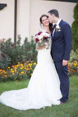 A romantic wedding couple shares intimate moments in a garden setting with yellow flowers and greenery.