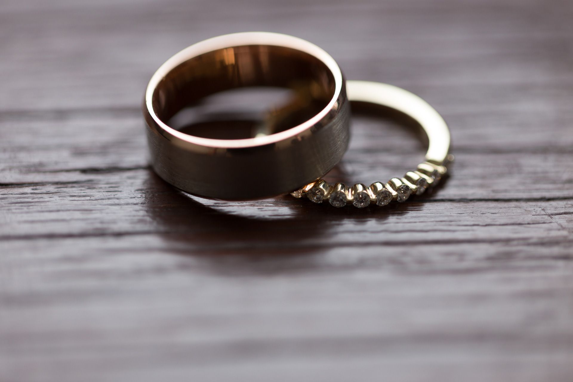 Wedding rings rest on a rustic wooden surface in a row, showing different angles and details of the bands.