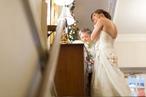 Bride in white dress walking through sunlit hallway with elegant interior details.