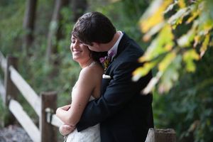 A couple shares a romantic kiss during an outdoor wedding ceremony surrounded by lush greenery.
