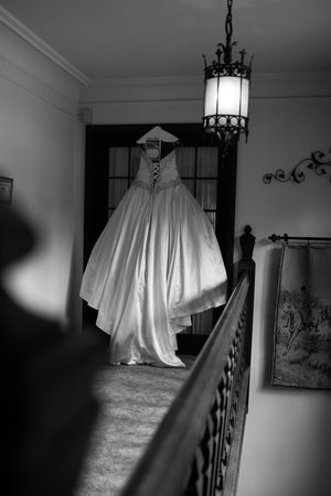 A series of black and white photos showing a wedding dress hanging in a dimly lit hallway with ornate details.