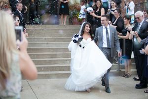Wedding party and guests gathered on stone steps during an outdoor ceremony.
