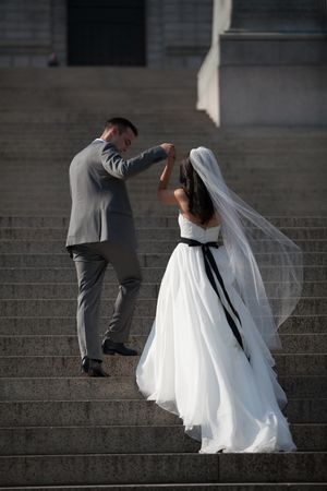 A couple in wedding attire poses on concrete steps during a photo session.