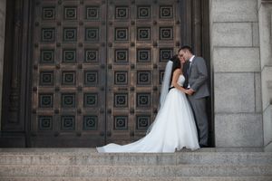 Wedding couple shares intimate moments against ornate architectural doors during their outdoor photo session.