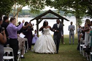 Outdoor wedding ceremony setup with white chairs and tent on a grassy lawn.