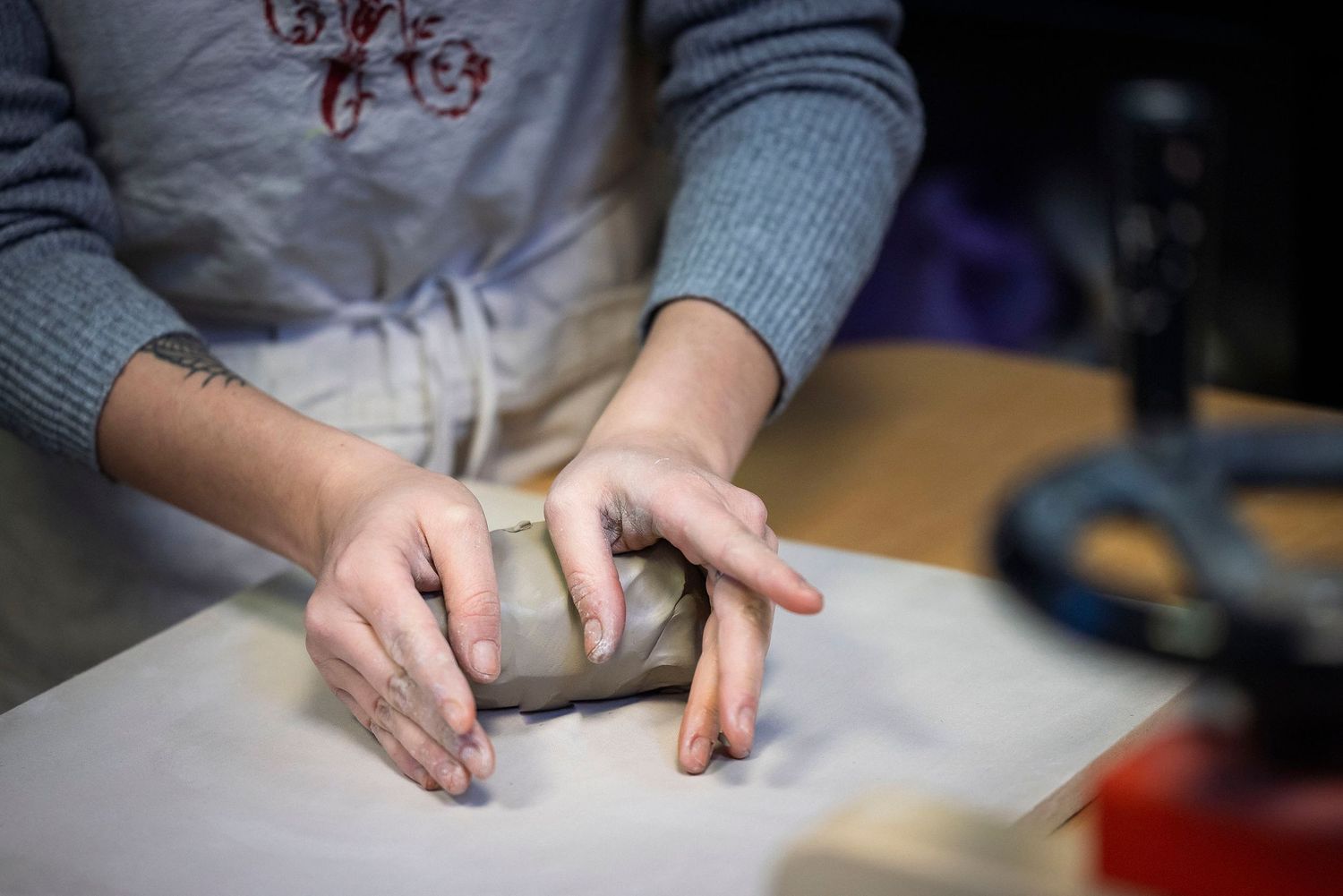 Hands working on a craft project at a wooden table with various materials.