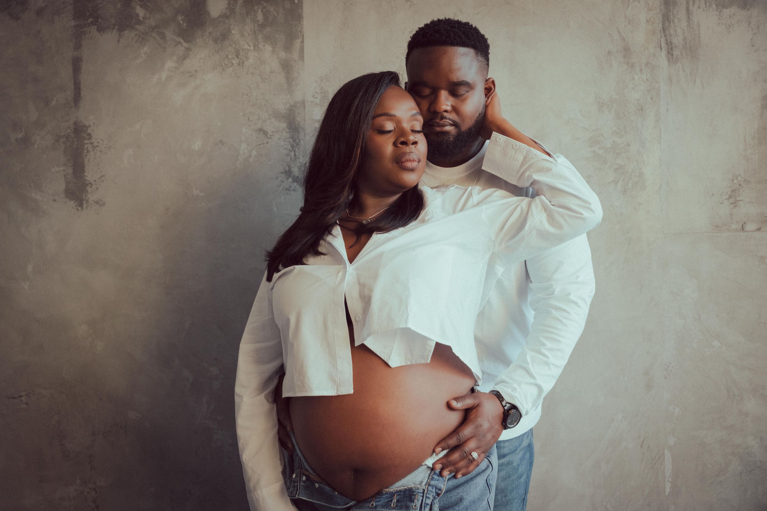 A series of romantic maternity photos showing an expectant couple embracing against a textured gray wall background.