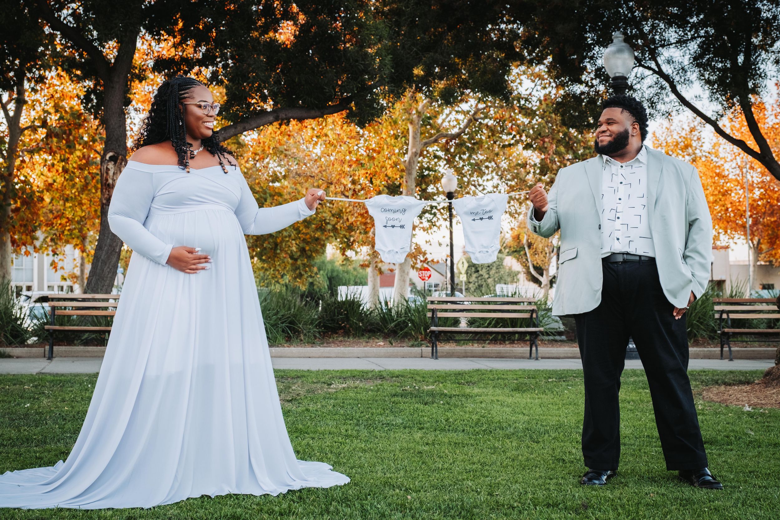 A couple in wedding attire dances together on a grassy lawn during golden hour sunset.