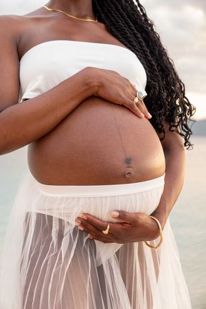 Close-up photos of a pregnant belly in white maternity dress showing progression of pregnancy against soft background.