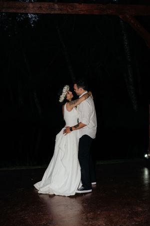 Bride and groom share romantic first dance outdoors at night, bride wearing floral crown.