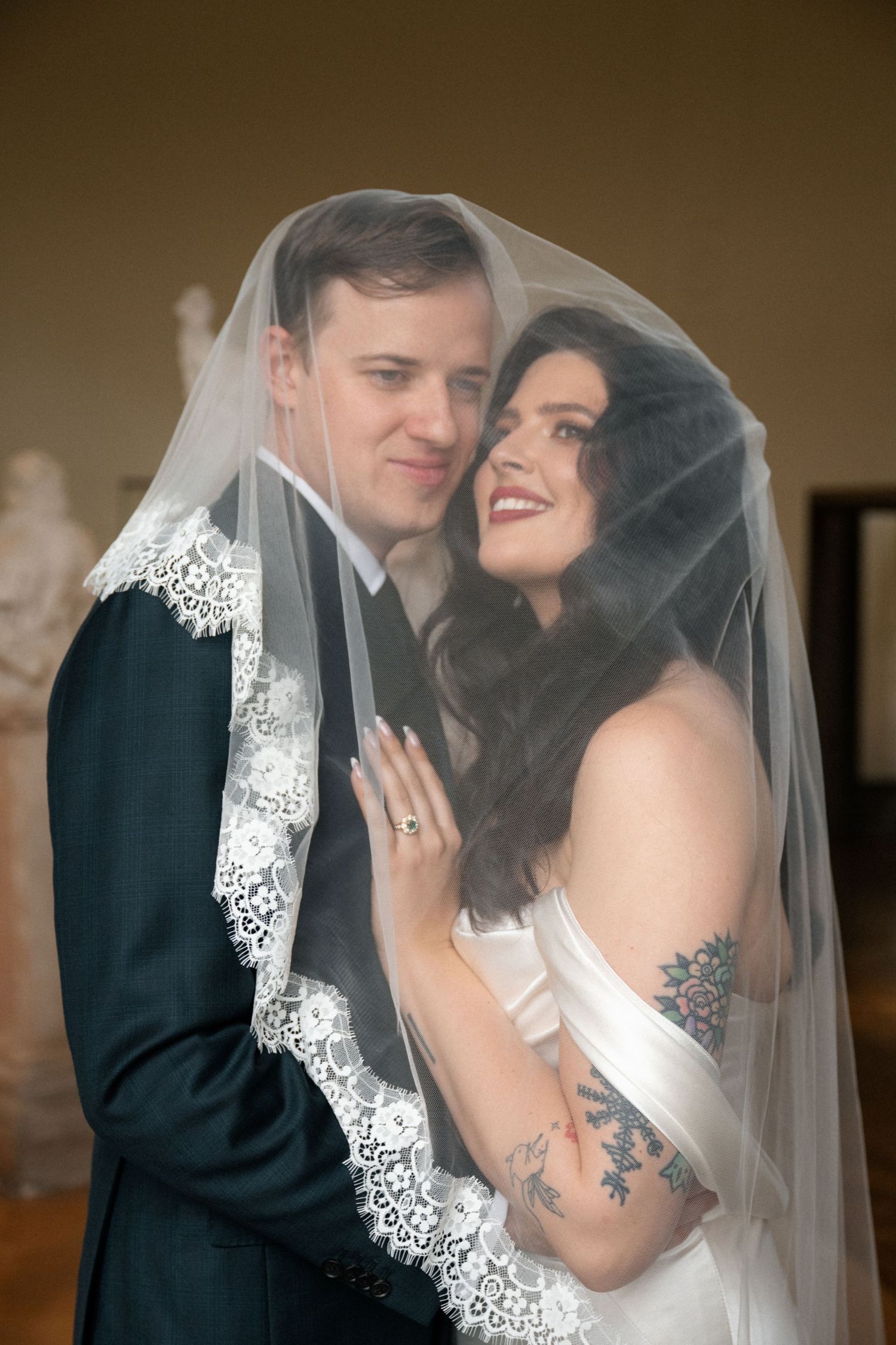 A happy couple shares an intimate moment under an elegant lace-trimmed wedding veil.