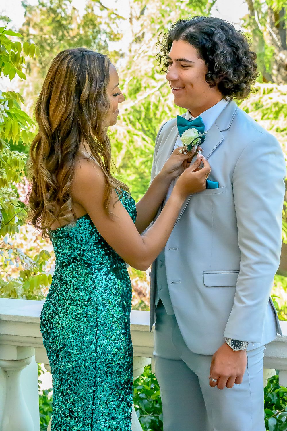 Couple in formal attire sharing a playful moment outdoors in springtime.