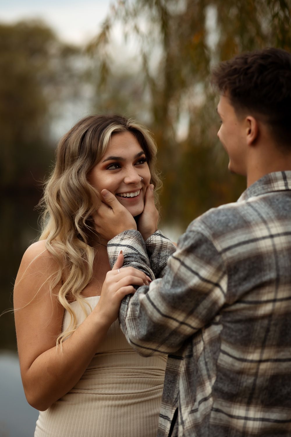 A couple shares joyful laughter and embraces while wearing casual attire in an outdoor setting.