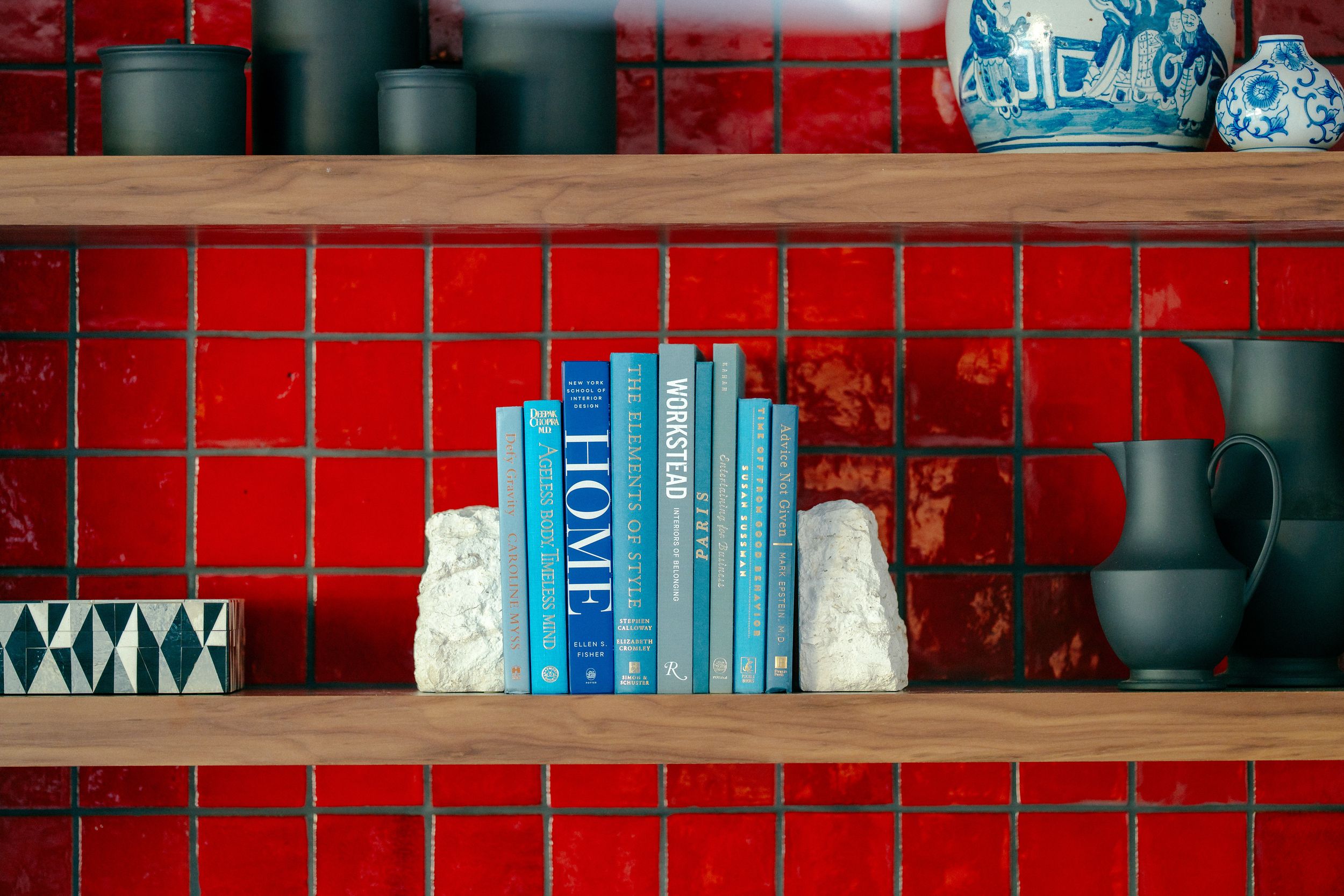 Rustic wooden shelves with vintage books and decor items against a vibrant red brick wall.