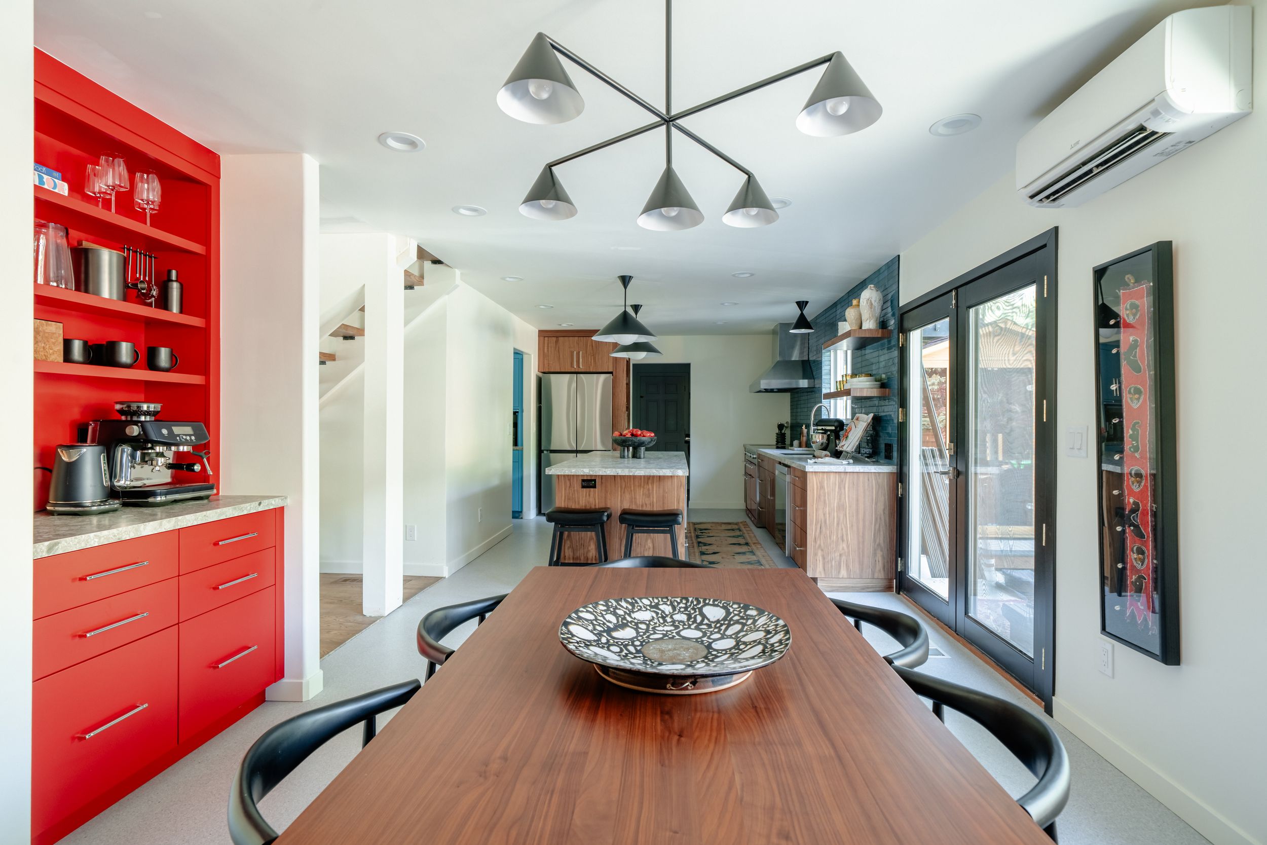 Modern kitchen interior with red cabinets, curved breakfast bar, and pendant lighting in an open concept space.
