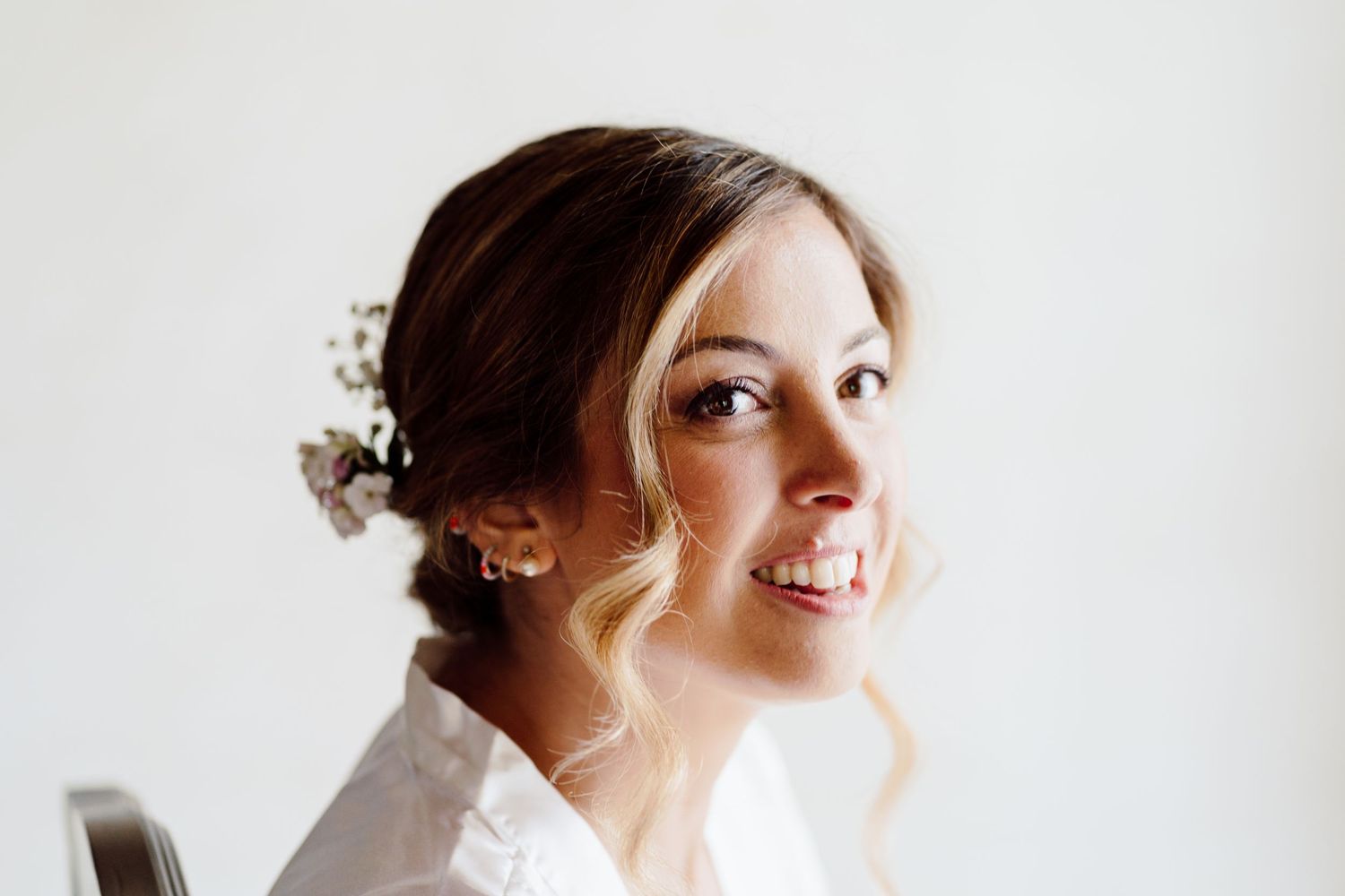 Smiling bride with floral hair accessories and pearl earrings on her wedding day.