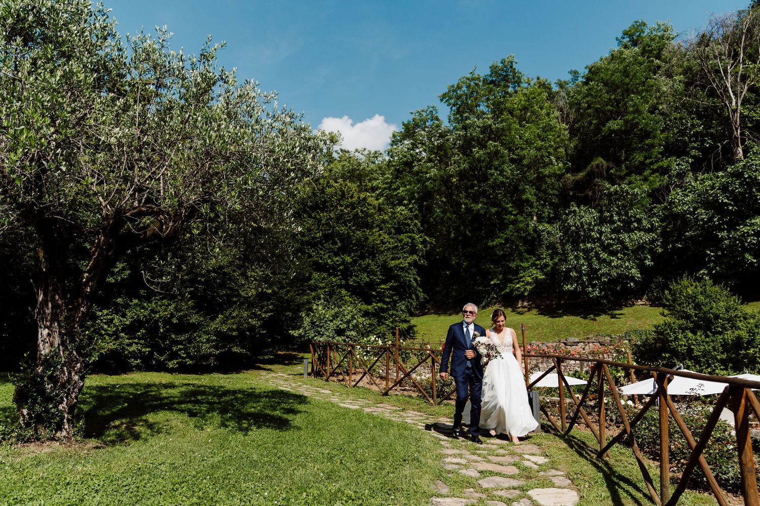 Bride and groom posing together on stone path in lush green garden on wedding day.