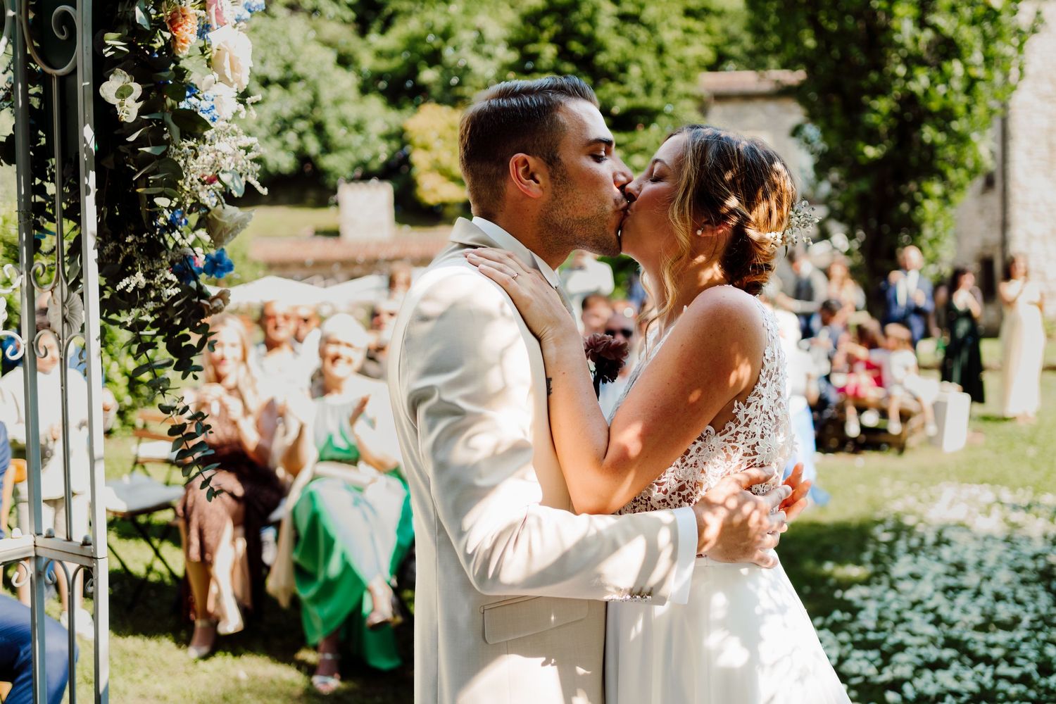 Bride and groom share their first kiss as a married couple during an outdoor wedding ceremony.