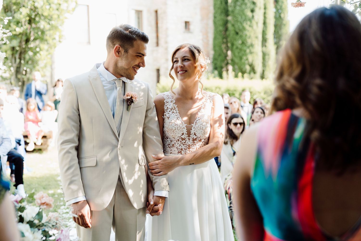 Smiling bride and groom walk hand in hand after their outdoor garden wedding ceremony.