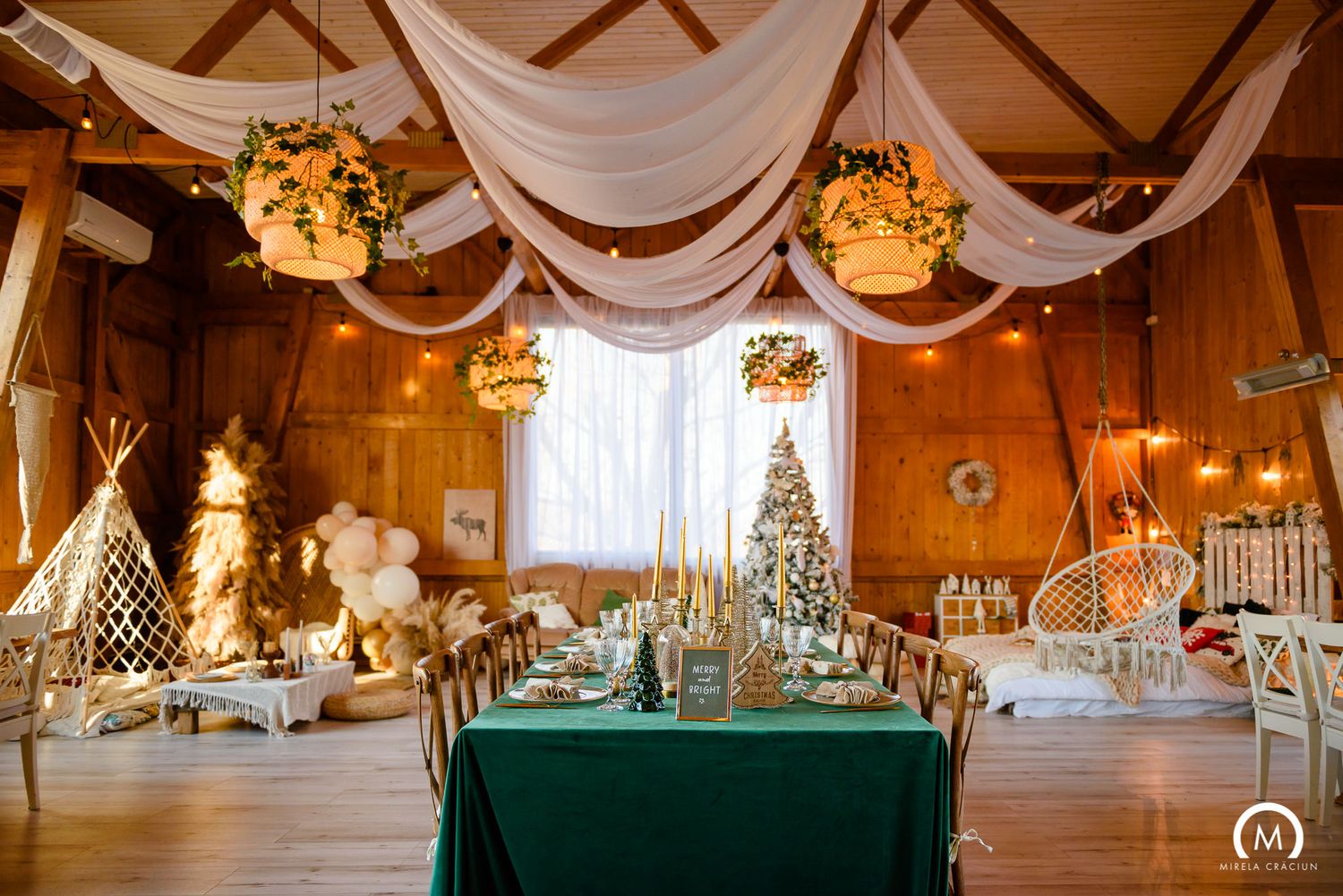 Rustic barn wedding venue decorated with white drapes, string lights and elegant table settings for a reception.
