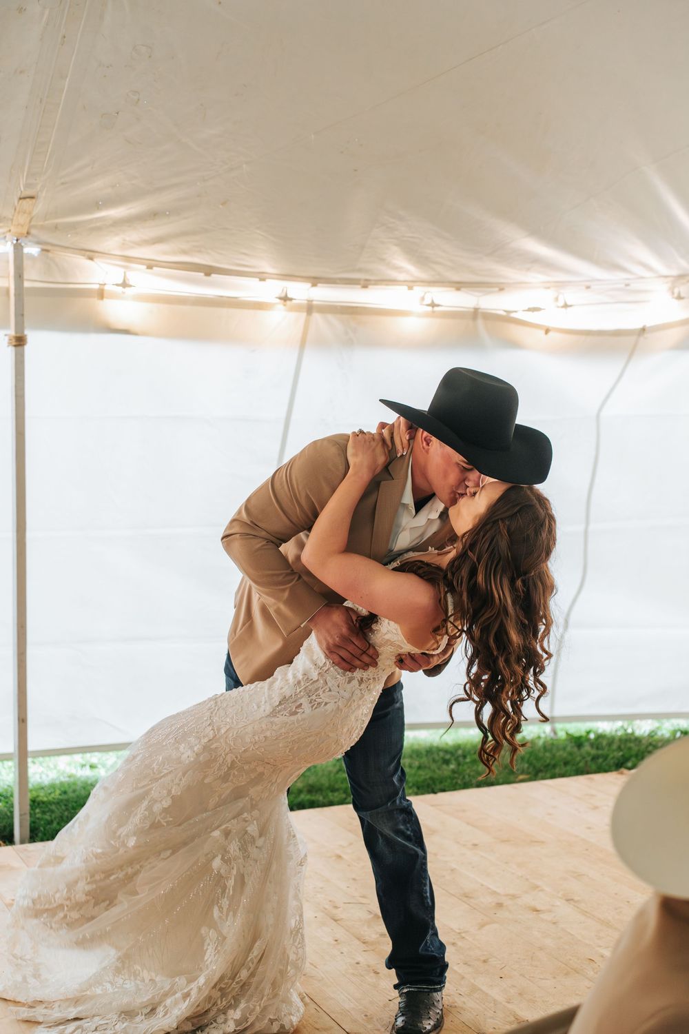 A romantic dip dance move between a couple at their wedding under a white tent.
