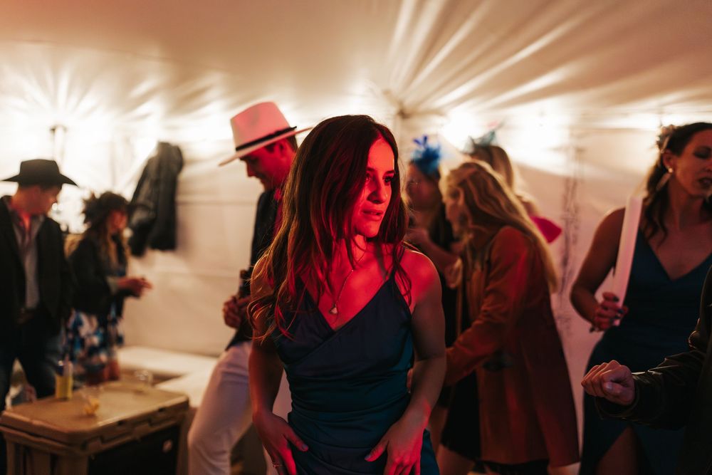 Wedding celebration with dramatic lighting and guests dancing in a covered venue.