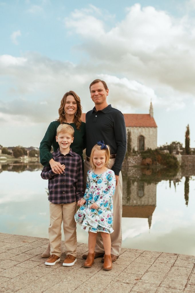 Family standing together on stone terrace overlooking historic European cityscape with church and buildings in background.