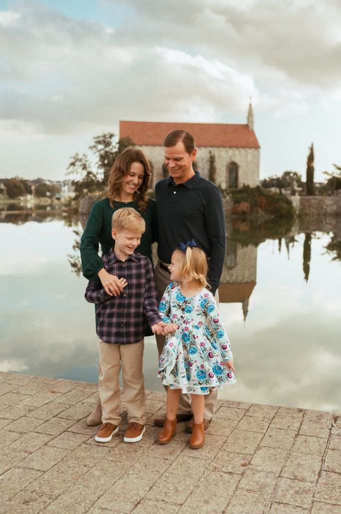 Family stands together on stone pavement during cloudy day with church building visible in background.
