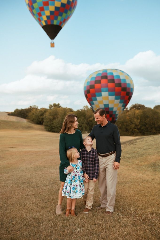 A vibrant patchwork hot air balloon provides a scenic backdrop in a grassy field.
