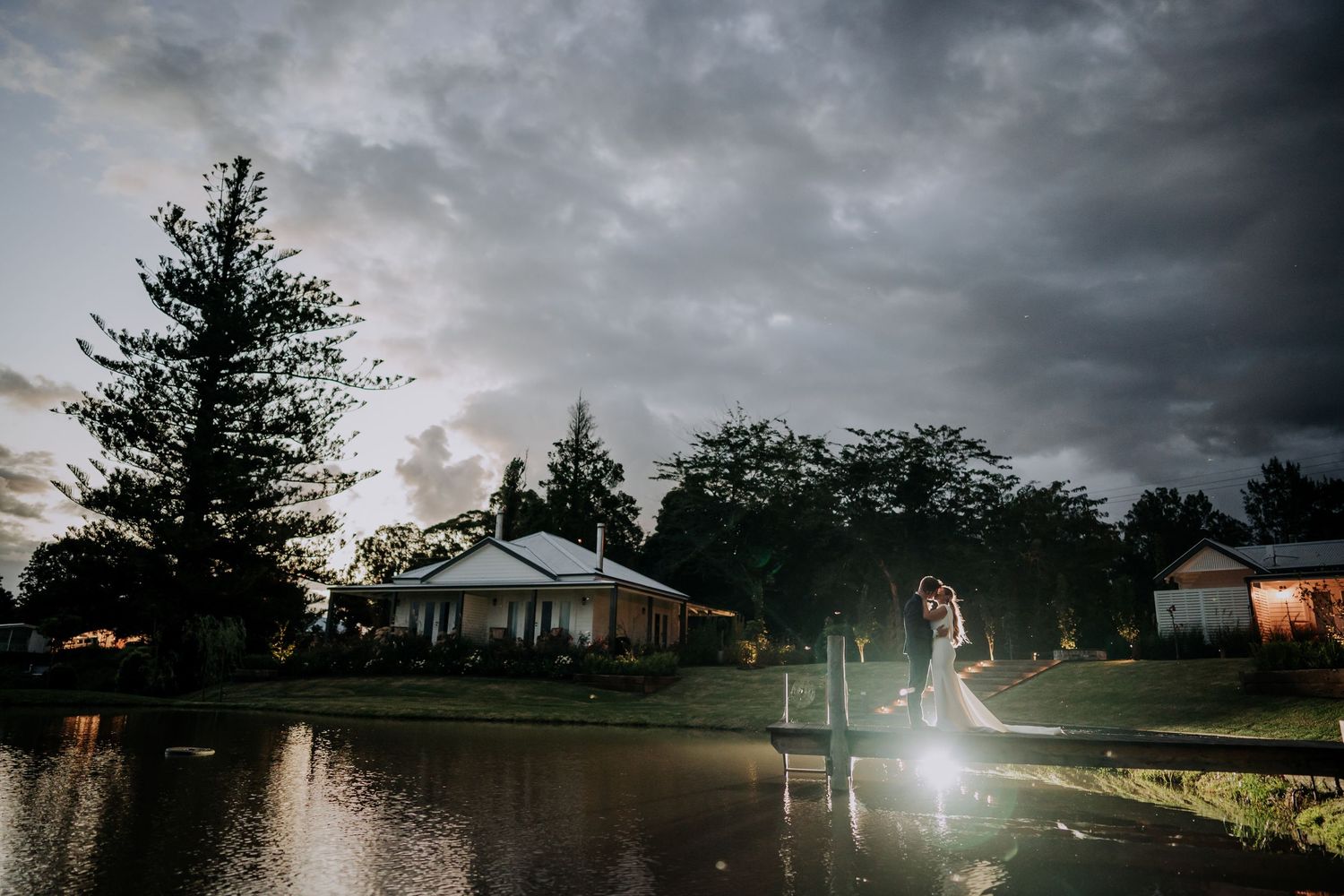 A romantic wedding photoshoot in front of a white building at sunset.