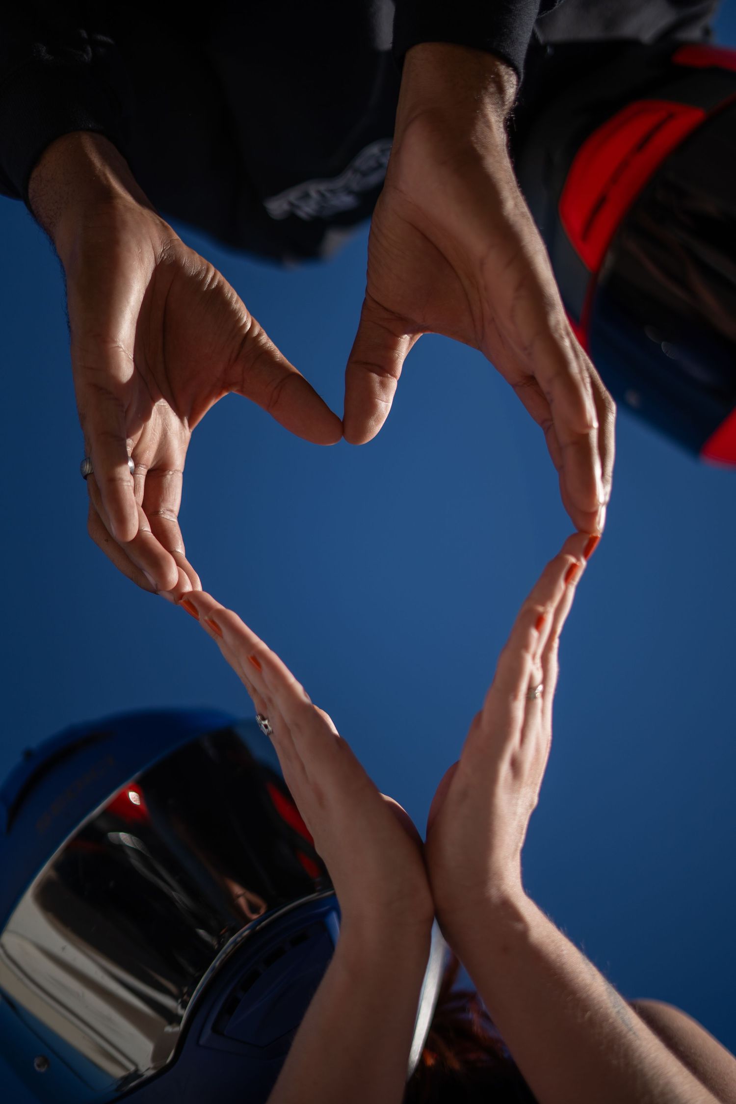 Multiple hands form a heart shape against a blue background in a creative photography composition.
