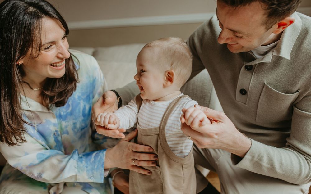 A family shares tender moments with their baby while sitting together on a couch at home.