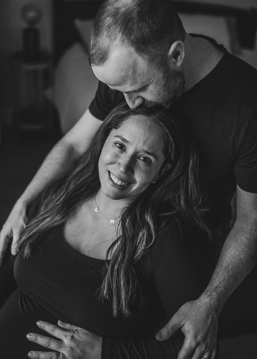 A series of black and white photos showing tender moments between a couple in an intimate indoor setting.