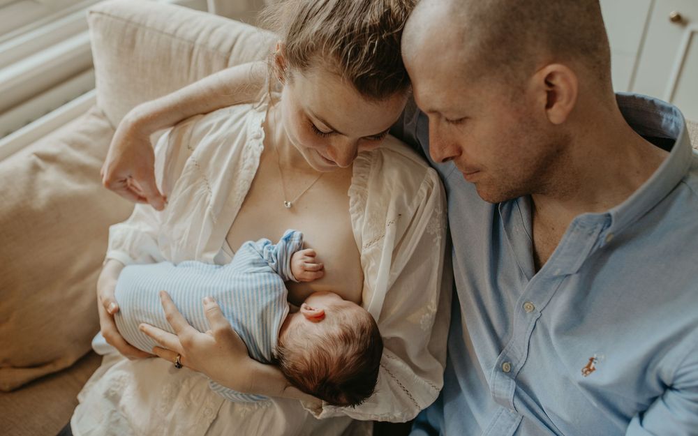 A tender family moment with parents and newborn baby in soft natural lighting.