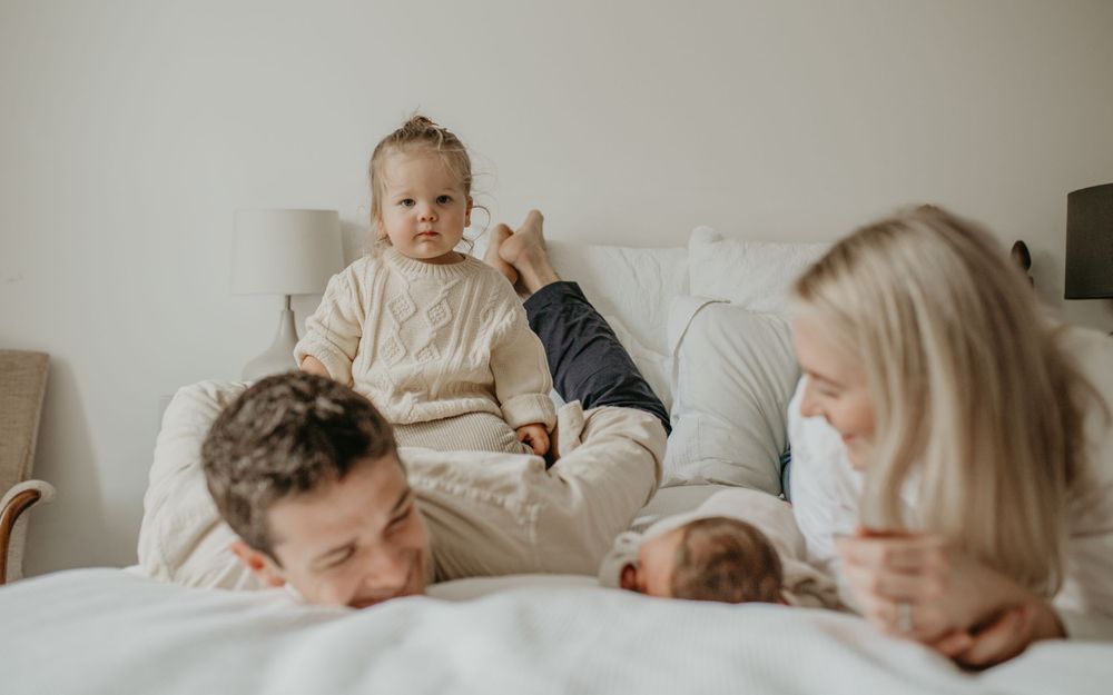 A tender moment captured in a series of intimate family photos on a white bed.