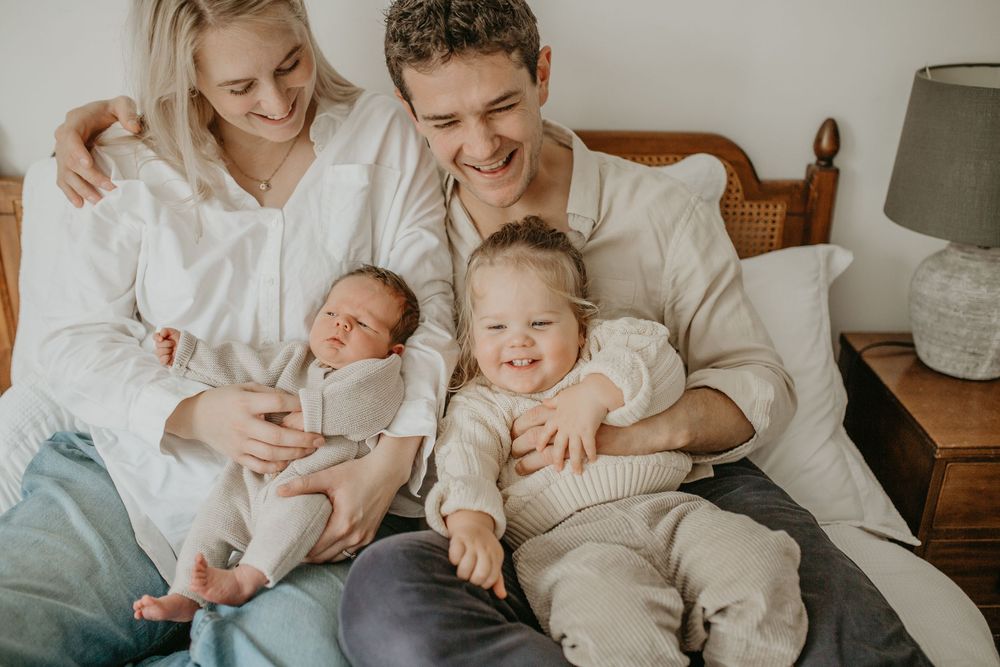 Family relaxing together on a cozy white couch while spending time with their baby.