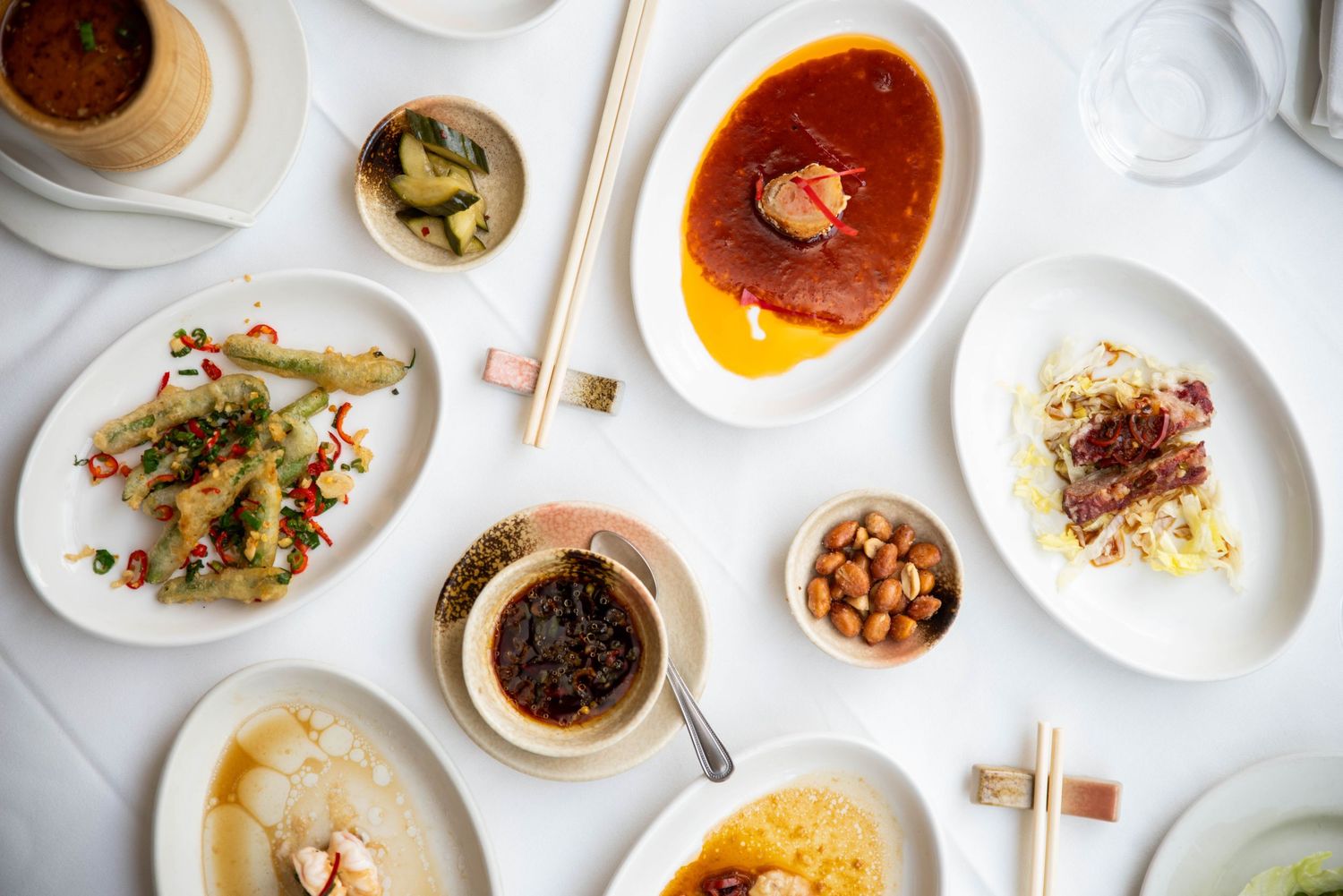 Overhead view of multiple elegant plated dishes arranged on a white table.