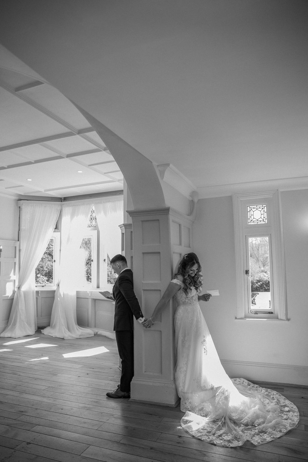 Black and white wedding photo sequence in a minimalist white room with natural lighting.