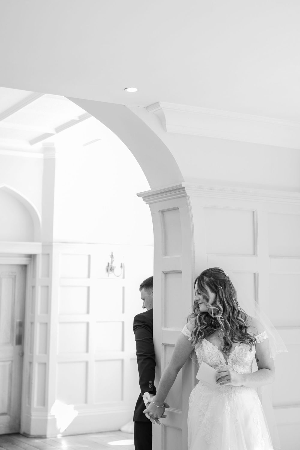 A bright white interior venue with elegant architectural arches and natural lighting.