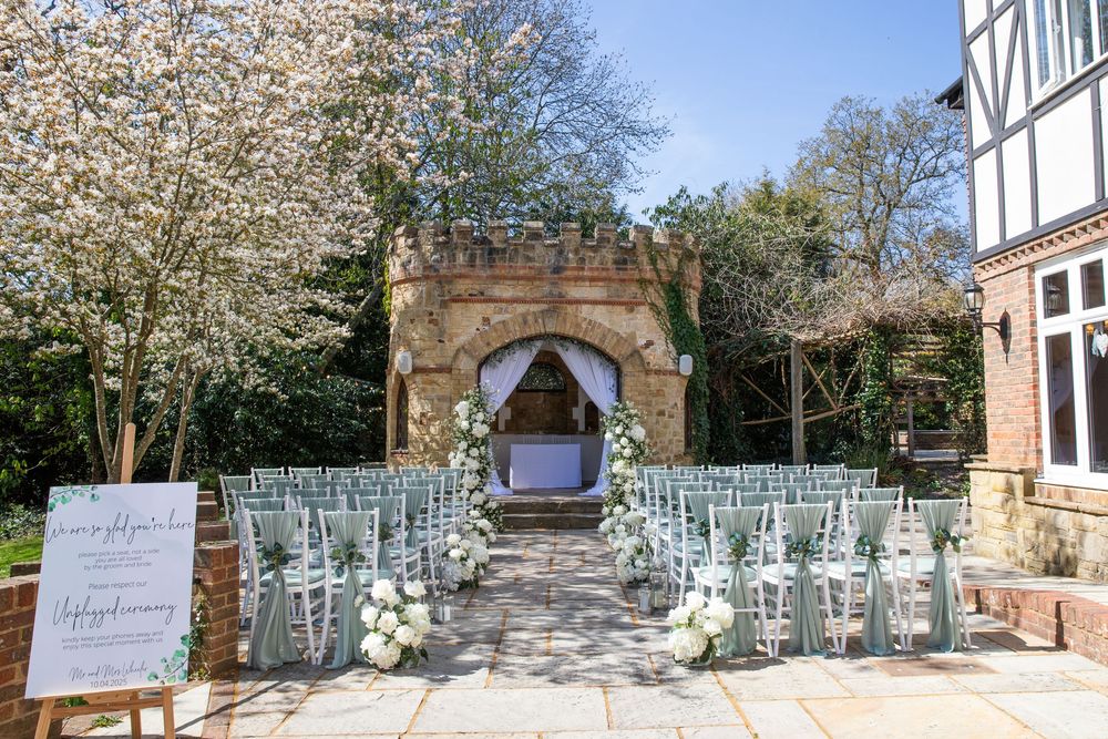 Outdoor wedding ceremony setup with white chairs and floral arrangements at a rustic venue.