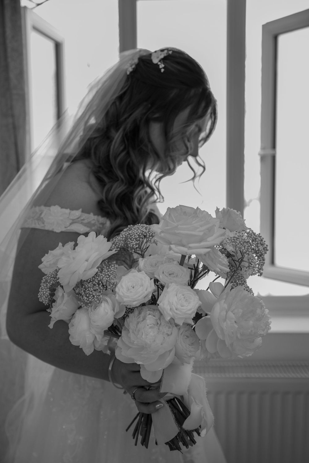 A series of black and white photos showing a bridal bouquet of white roses and delicate flowers against a window.
