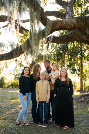 Family gathering under a large oak tree with Spanish moss in natural lighting.
