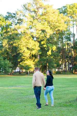 People walking together across a sun-lit grassy field with trees in the background.