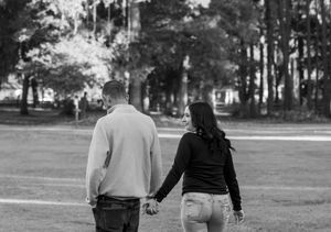Black and white image of people walking together on a tree-lined path.