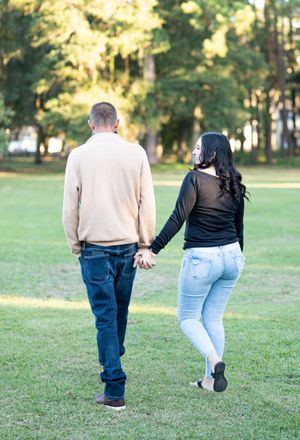 Couple walking together on grass in a park during golden hour.