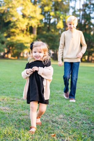 Child running and playing on grass in autumn sunlight.